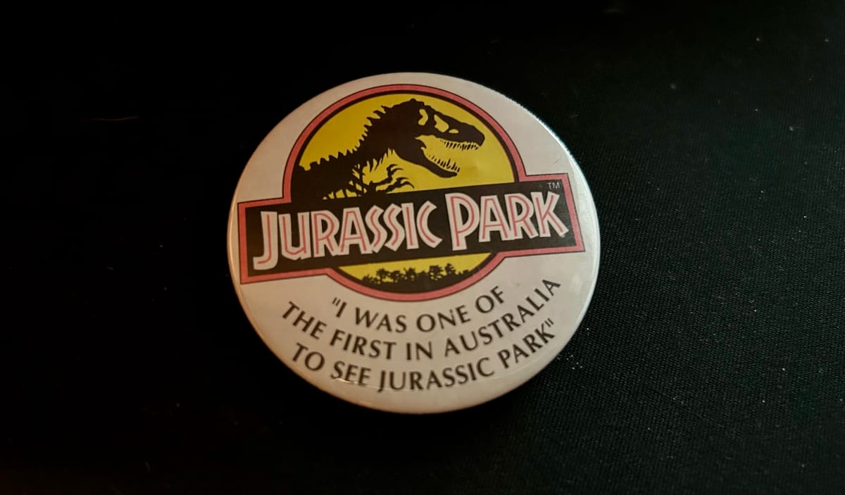 A white badge that bears the JURASSIC PARK logo, and underneath, the words "I WAS ONE OF THE FIRST IN AUSTRALIA TO SEE JURASSIC PARK"